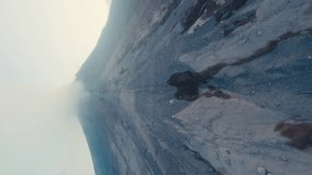 Vertical video. Aerial morning view peak smoke crater active erupting volcano with rocky slopes steam. Powerful wild nature environmental disaster. Volcanic fault with cooling black lava sunrise 4k