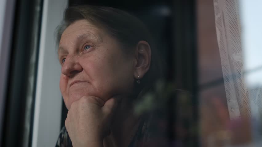Pensive sad elderly woman at the window, close-up Royalty-Free Stock Footage #1110739303