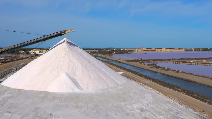 The newly produced salt from the salt pans in Aigues Mortes, France, is transported on a conveyor belt on the top of a salt pile, a so-called camel or pyramid - wide shot, steadicam