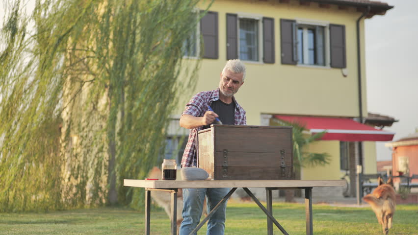 Hobby happy mature man restores old furniture in the home garden,caucasian male enjoying time varnishing painting antique cabinet in the backyard slow motion | Shutterstock HD Video #1110742507