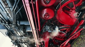 Wheels of steam coal locomotive at railroad station. Wheels and machinery of historic German engine passenger train at train track. Retro historic train preparing to leave station. Vertical video