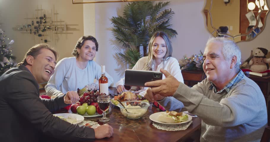 Latin family taking a self-portrait with their smartphone. They smile in front of the smartphone camera. Royalty-Free Stock Footage #1110743239
