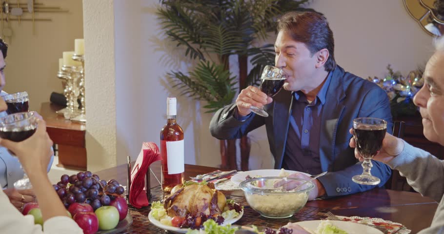 Latin family chats and enjoys food and drinks at Christmas dinner. Royalty-Free Stock Footage #1110743241