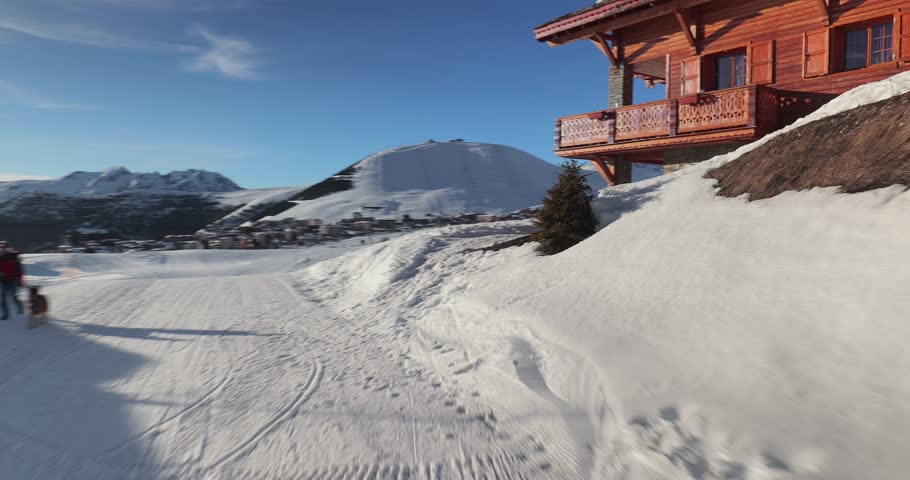 Skiing slope in the French Alps, passing by wooden chalets for accommodation in Alpe d