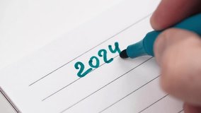 closeup of man hand writes the numbers 2024 with a blue felt-tip pen in a notebook in a ruler. concept of planning, motivation and setting goals for the coming year. selective focus. - Powered by Shutterstock - Get 15% off with code: PIKWIZARD15