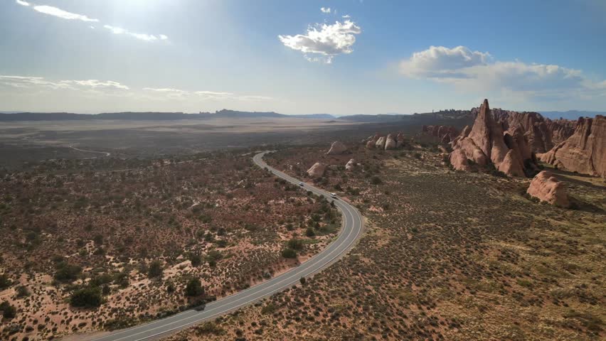 Drone video showcasing a car journeying through the picturesque terrain of Arches National Park.