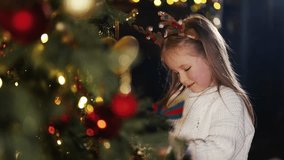 Smiling little cute girl in deer antlers headband decorating Christmas tree playing with toys admiring garlands lights. New Year Xmas traditions happy childhood home family holiday atmosphere concept. - Powered by Shutterstock - Get 15% off with code: PIKWIZARD15