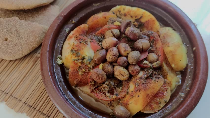 A traditional beef meat tajine, tagine, meal served in a Moroccan clay pot, hot, and sizzling. Traditional Moroccan slow-cooked meal with beef | Shutterstock HD Video #1110761571
