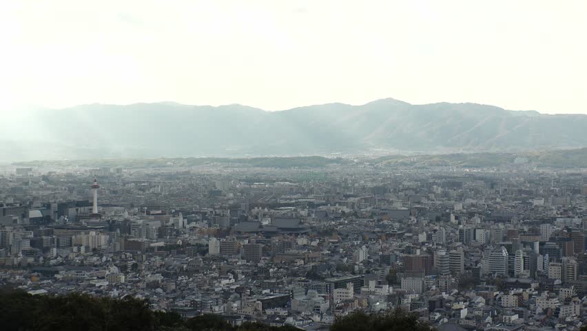KYOTO, JAPAN - DEC 2021 : Aerial panoramic view of Kyoto city in daytime. Scenery of mountain, streets and buildings around downtown area. Japanese nature and traditional old town concept video.