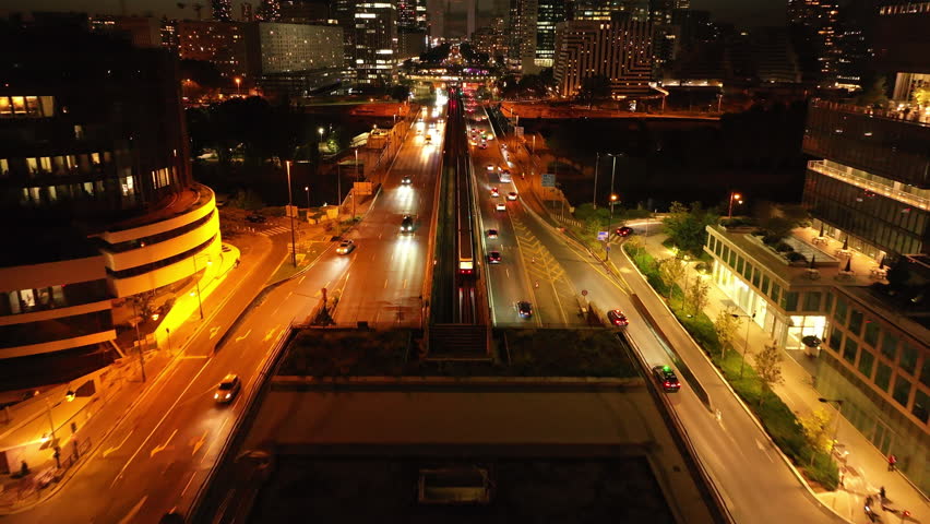 Forwards tracking of subway train driving on tracks in center of multilane road in modern urban district. Skyscrapers in La Defense at night. Paris, France Royalty-Free Stock Footage #1110772353