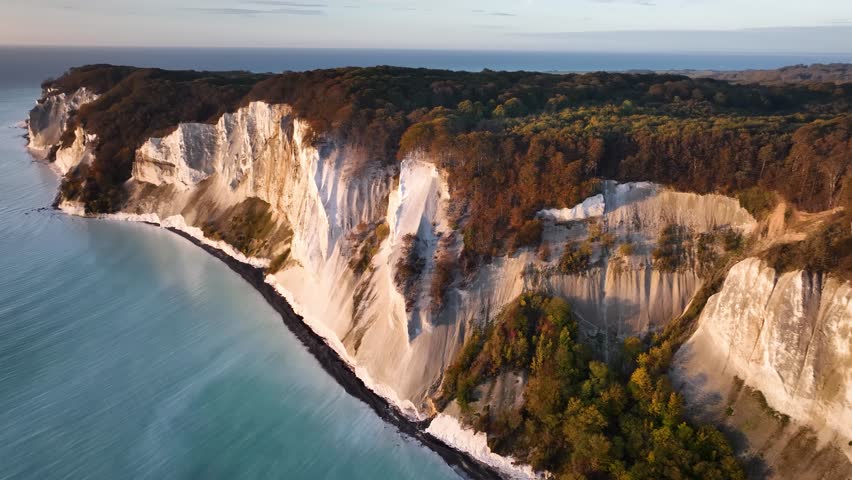 Aerial footage of the magnificent chalk cliffs of Møns Klint, rising high above the Baltic Sea. Denmark's highest cliff suspended over the turquoise waters of the Baltic Sea in full view landscape. Royalty-Free Stock Footage #1110772867