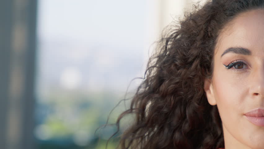 Happy millennial girl portrait with wind blowing curly hair. Half face portrait of beautiful smiling confident young latino ethnic woman. Close up of pretty face looking at camera posing alone outside Royalty-Free Stock Footage #1110775363