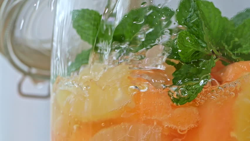 Make white sangria by pouring wine into a glass jar filled with fresh fruit. Close-up and slow motion. Fresh mint, pineapple, red-fleshed melon, and grapefruit | Shutterstock HD Video #1110782047
