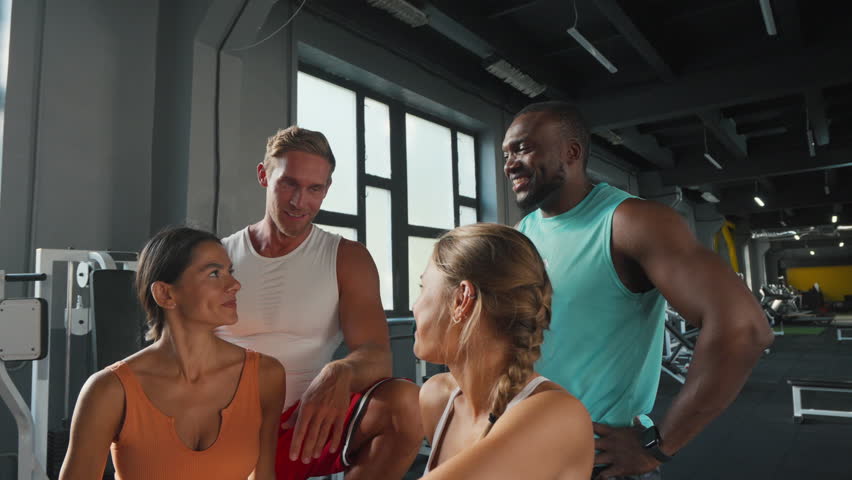 Athletes give high fives after finishing intense workout. Sportsmen and sportswomen celebrate new personal records in fully-equipped gym
