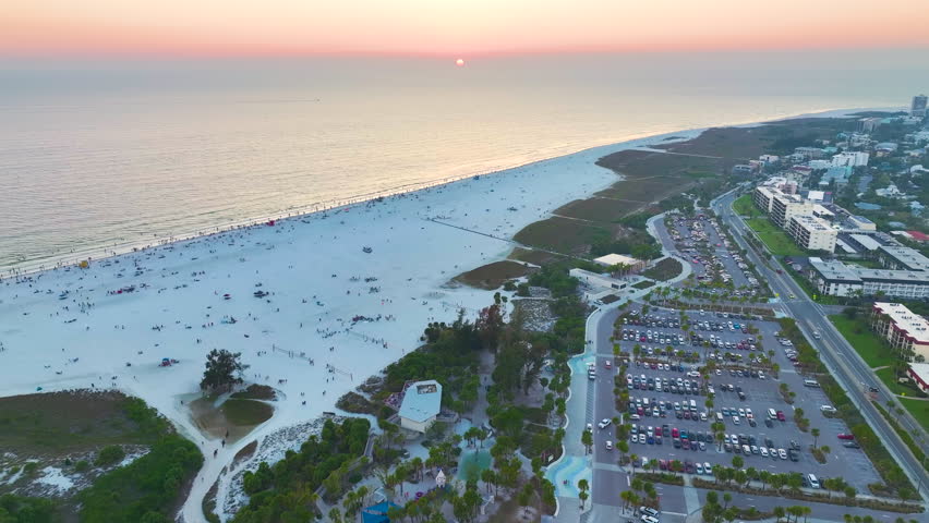 Parking lot for tourists cars in front of famous Siesta Key beach with soft white sand in Sarasota, USA at sunset. Popular vacation spot in warm Florida