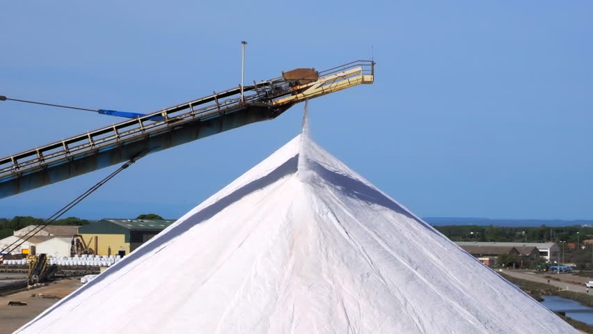 The newly produced salt from the salt pans in Aigues Mortes, France, is transported on a conveyor belt on the top of a salt pile, a so-called camel or pyramid - closeup, steadicam