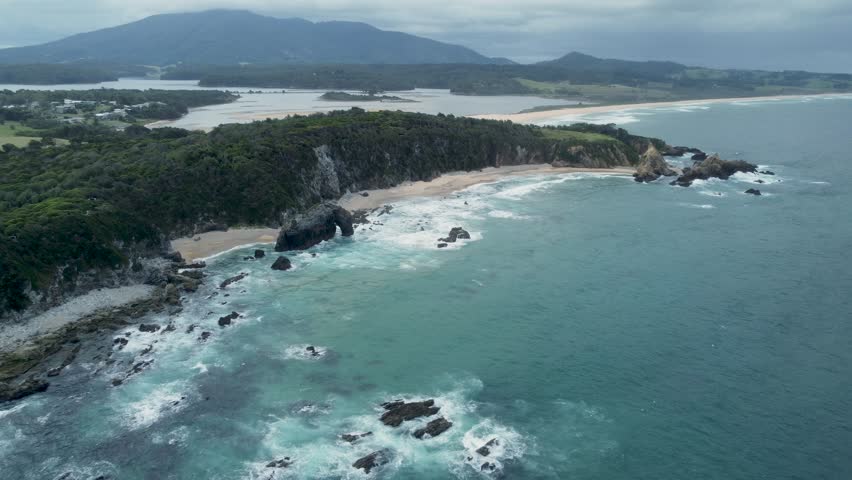 Panoramic aerial view of famous Australian beach with rock formation surrounded by beautiful mountain landscape