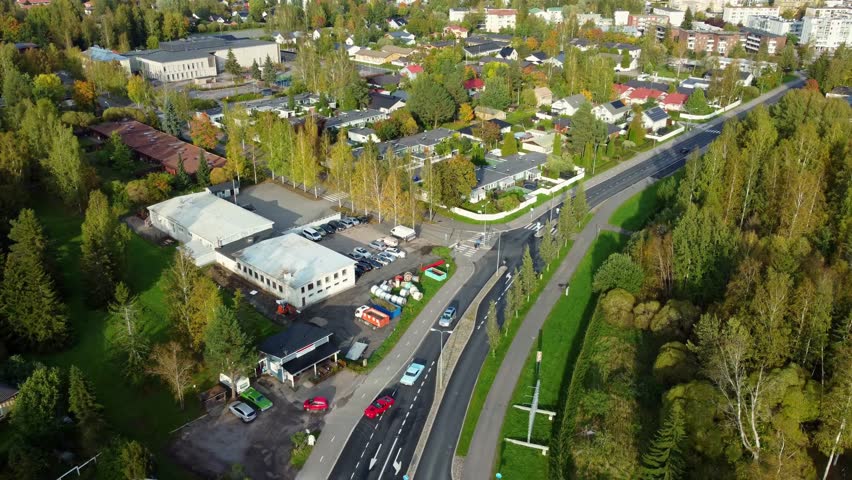 Aerial view of a pair of classic and flashy cars entering a parking lot in a rural town on a sunny spring day, Kerava in Finland.