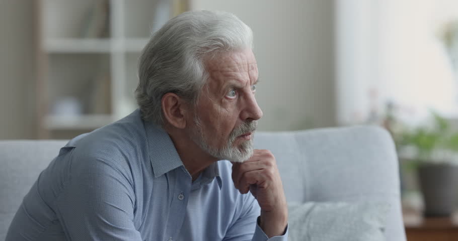 Serious thoughtful grey haired older senior man thinking on healthcare, bored retirement, making decision, feeling doubts, looking away, touching chin, sitting on couch at home Royalty-Free Stock Footage #1110791311