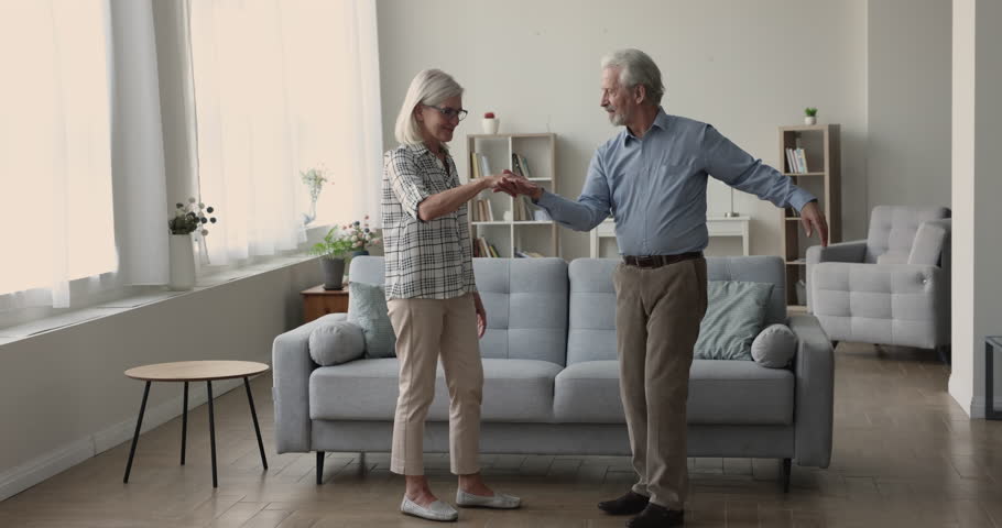 Happy senior retired husband and wife dancing to music, spinning around in living room, having fun, training pair social dance, enjoying home party, activity, date, celebrating anniversary Royalty-Free Stock Footage #1110791361