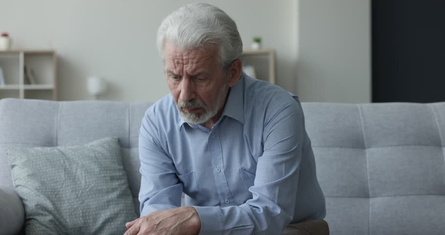Sad lost grey haired elderly retired man suffering from depression, memory loss, mental Alzheimer disorder, sitting on home couch with pointless stare, looking away, thinking on geriatric disease Royalty-Free Stock Footage #1110791371