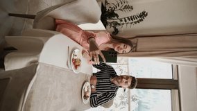 A couple in love has breakfast in the morning in a restaurant on the buffet line. Breakfast in a hotel. Concept of relaxation in a hotel. Vertical video 