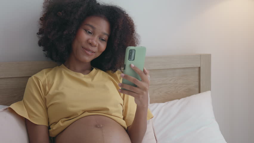 An African pregnant woman radiates love as she happily shows her baby