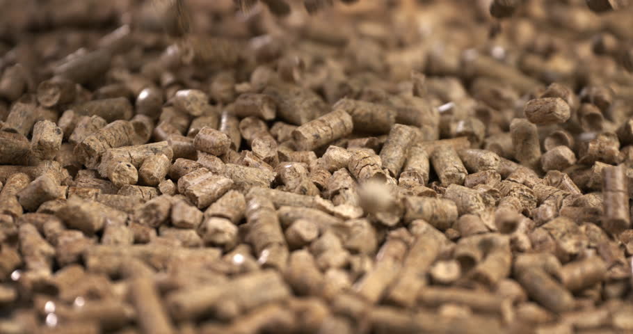 wood heating; falling wood pellets against black background. slow-motion  about small pieces of compress wood and renewable energy sources for warm houses and hot water at home.