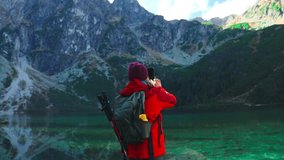 Tourist hiker woman backpacker on rock enjoying taking selfie with smartphone near the view of mountain lake Morskie Oko in Tatra National Park, Poland. Adventure, travel, holiday concept. High - Powered by Shutterstock - Get 15% off with code: PIKWIZARD15