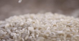 Super slow motion macro of dry basmati quality rice falling on rustic wooden table on restaurant kitchen. Macro, 4K, ,Very Close-up, 1000 fps video.