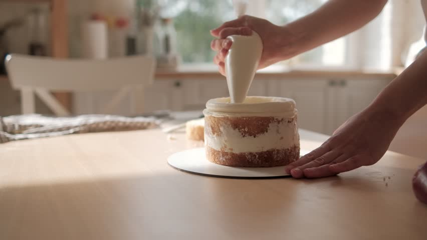 Confectioner woman is pouring cream on sponge cake using pastry bag, closeup view. Pastry chef is cooking homemade cake. cooking, baking and cooking, home cooking. Royalty-Free Stock Footage #1110807671