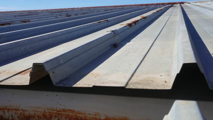 Rusty roof. Corrugated steel panels – oxidized galvanized metal sheets on the outer wall of a production workshop or warehouse. Rusty pattern of an aged iron roof Royalty-Free Stock Footage #1110808639