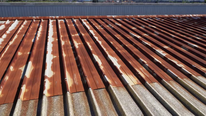 Rusty roof. Corrugated steel panels – oxidized galvanized metal sheets on the outer wall of a production workshop or warehouse. Rusty pattern of an aged iron roof Royalty-Free Stock Footage #1110808641