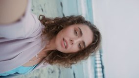 Lifestyle blog, fashion influencer, beauty blogger, travel vlog concept. Mobile camera vertical video of beauty woman touching her face. Gorgeous female boho style enjoying ocean beach in California - Powered by Shutterstock - Get 15% off with code: PIKWIZARD15