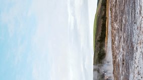The Great Geysir eruption in slow motion. Tourists observe the spectacular flow of hot water from the ground. Strokkur geyser, periodically spouting hot spring. 4k stock footage. Vertical clip.