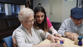 Nurse helping to old people to resolve skill games