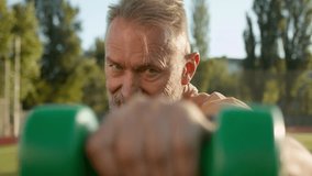 Confident old Caucasian man workout dumbbells weight arm training sport sportsman bodybuilder strength exercising physical athlete strong equipment muscular power vitality stadium city outdoors effort - Powered by Shutterstock - Get 15% off with code: PIKWIZARD15