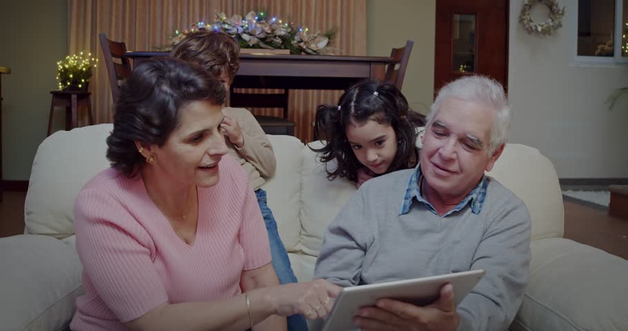 Grandparents share a movie with their grandchildren that they watch sitting on the couch in the family room of the house. Royalty-Free Stock Footage #1110811953