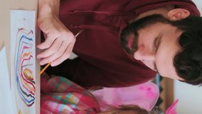 Vertical video. Painting education. Parent learning. Father man teaching daughter little girl in fairy princess costume colors develop creative skills at table.