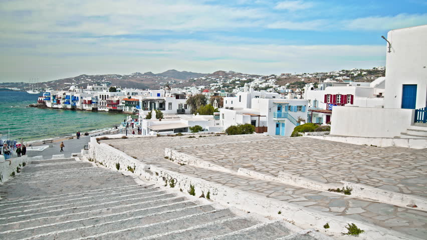 Cinematic view of the Mykonos landscape featuring the turquoise sea with whitewashed houses in the background. Panoramic view of the Mykonos Island in the Cyclades group in the Aegean Sea. 