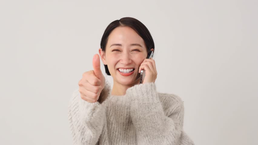 Asian middle aged woman with the smartphone thumbs up gesture in white background Royalty-Free Stock Footage #1110815887