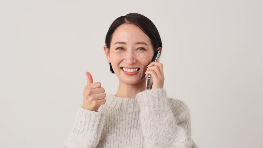 Asian middle aged woman with the smartphone thumbs up gesture in white background Royalty-Free Stock Footage #1110815889