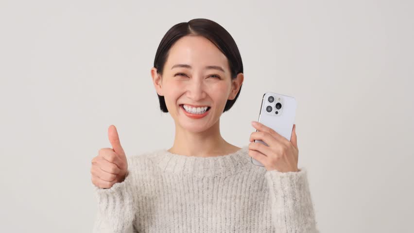 Asian middle aged woman with the smartphone thumbs up gesture in white background Royalty-Free Stock Footage #1110815921