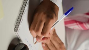Vertical video Man at home paying attention in elearning seminar teleconference with teacher, writing on notepad. Homeschooling student listening to lesson while doing his homework tasks - Powered by Shutterstock - Get 15% off with code: PIKWIZARD15