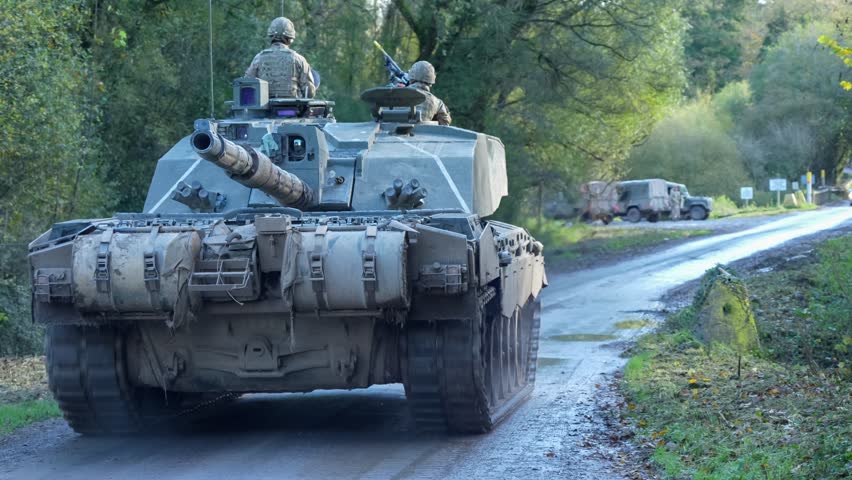 Close-up of three British army Challenger II 2 FV4034 main battle tanks moving along a narrow country lane