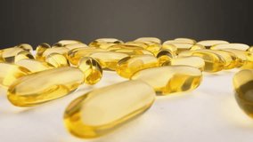 Capsules with important vitamins and minerals to improve health. Vitamin D and the omega 3 fatty acid group. Fish oil in the varmaceuceutical capsule form, yellow in color, in a transparent shell.