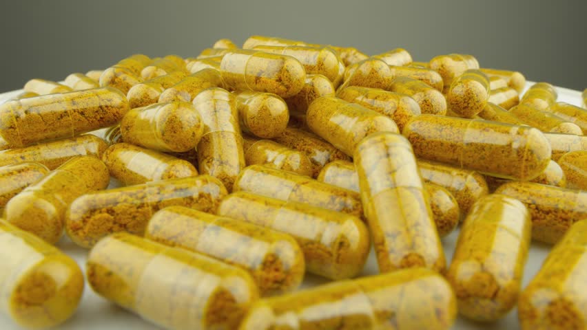 Curcumin and other nutrients in clear capsules rotate on the platform. Maintaining a healthy lifestyle and sports nutrition. Cleansing the body and treatment with natural supplements