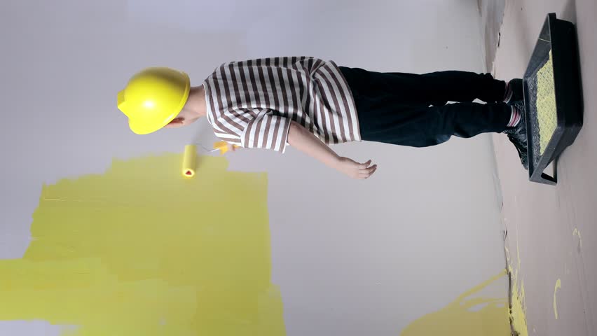 Boy painting wall for yellow paint during home renovation.