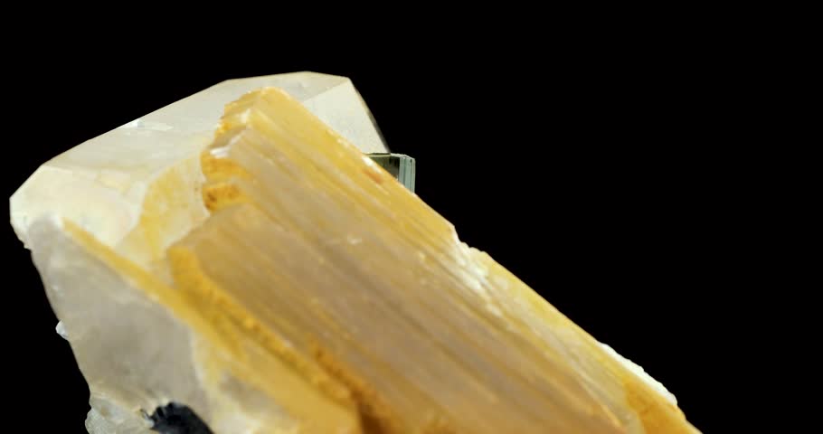 Elbaite verdelite (green tourmaline), on quartz and muscovite rotating in 4k isolated on black background. macro detail close-up rough raw unpolished semi-precious gemstone. 