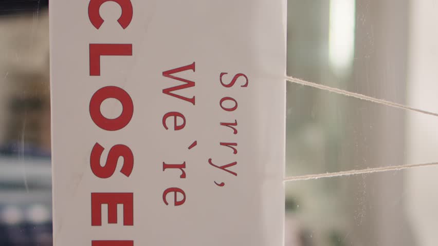 Vertical video Extreme close up shot of close sign in luxurious clothing store with elegant assortment of shirts. Sorry we are closed message on premium fashion boutique door with trendy stylish
